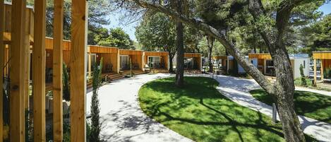 A modern outdoor area with wooden structures, a paved walkway, and a well-maintained lawn.