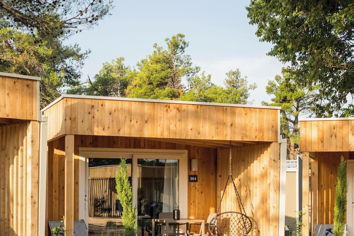 Une cabane en bois dotée d’une véranda, d’un coin repas et d’un espace salon.