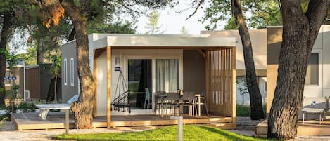 A modern outdoor seating area with a wooden deck, a swing, and a covered seating space with chairs and a table.