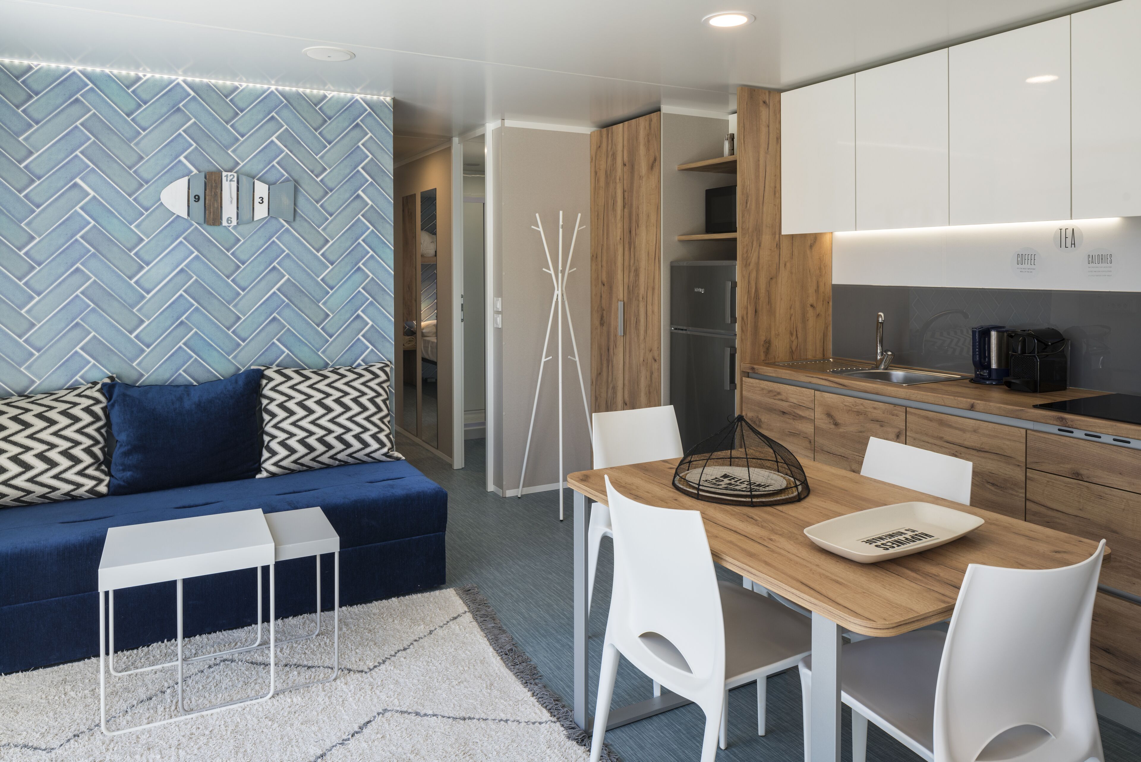A modern kitchen with white cabinets, a wooden dining table, and a built-in oven.