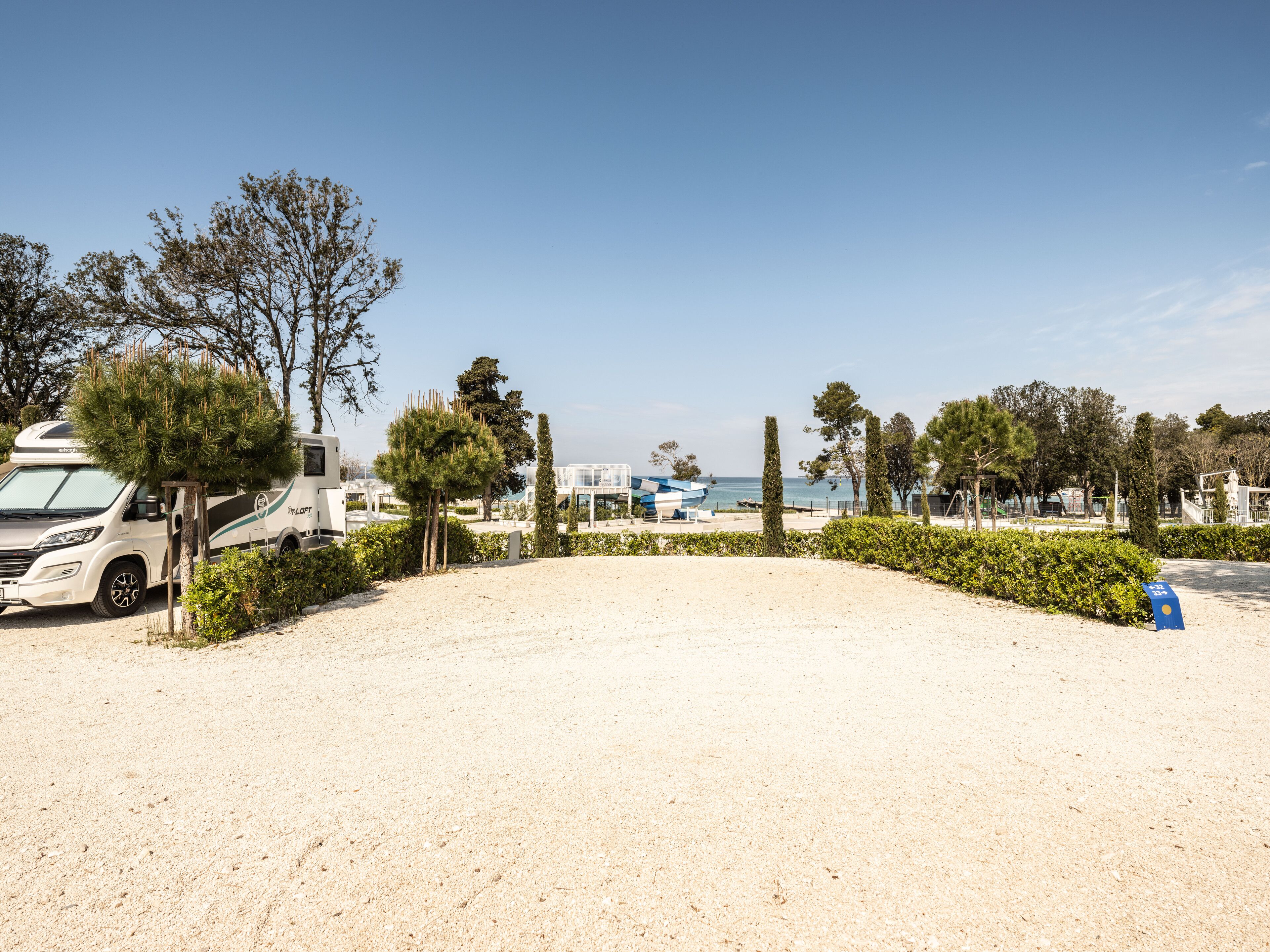 A campground with RVs, a sandy beach, and a clear blue sky.