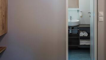 A hotel room with a bed, a bathroom visible through an open door, and a blue carpeted floor.