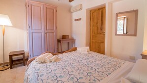 Ein Schlafzimmer mit einem Bett, einem Holzschrank, einem kleinen Tisch und einem Fenster.