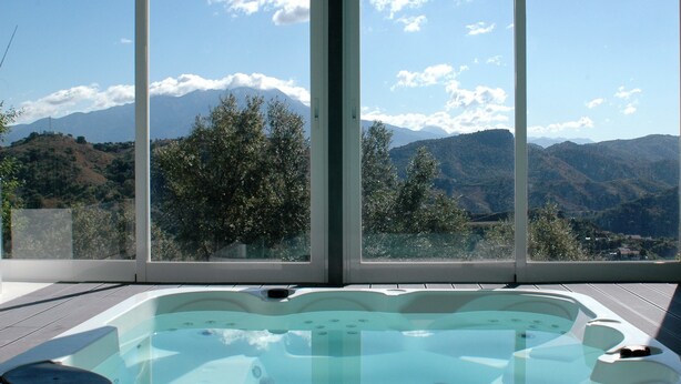 A hot tub with a mountain view through large windows. - Jingtu Wellness & Spa Resort (Comares)