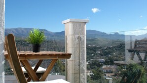 A wooden table with a potted plant, a stone pillar, and a view of a mountainous landscape. - Jingtu Wellness & Spa Resort (Comares)