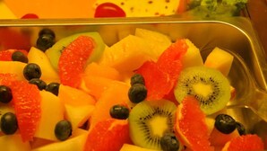 A metal tray filled with assorted fruits including kiwi, blueberries, and orange segments. - Harburger HOF (Hamburg)