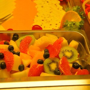 A metal tray filled with assorted fruits including kiwi, blueberries, and orange segments. - Harburger HOF (Hamburg)