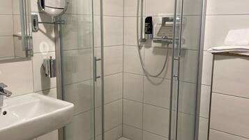 A modern bathroom with a glass-enclosed shower, a white sink, and a toilet.