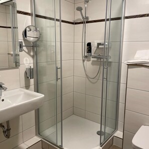 A modern bathroom with a glass-enclosed shower, a white sink, and a toilet. - Harburger HOF (Hamburg)