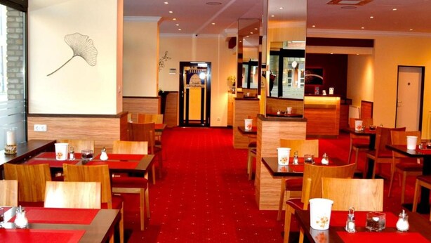 Un vestíbulo de hotel con alfombra roja, mobiliario de madera y una pared con diseño de hojas.