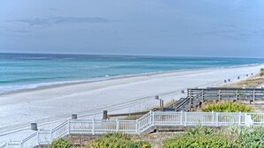 Une plage bordée d’une clôture blanche, avec une promenade en bois et une vue sur l’océan.