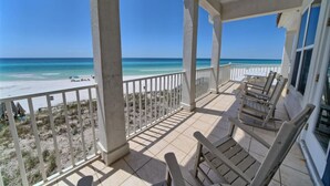 Un balcon fermé offrant une vue sur la plage et l’océan.
