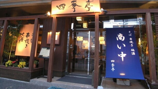 A restaurant entrance with traditional Japanese signage and a blue banner.