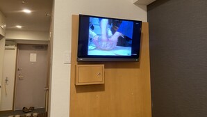 A television mounted on a wall with a wooden panel below it.