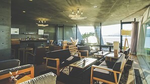 A modern interior with a bar area, seating, and large windows offering a view.