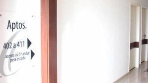 A corridor with a sign indicating 'Aptos. 402 a 411' and 'acesso ao 5º andar pela escada'. - Hotel Obino São Borja (São Borja)