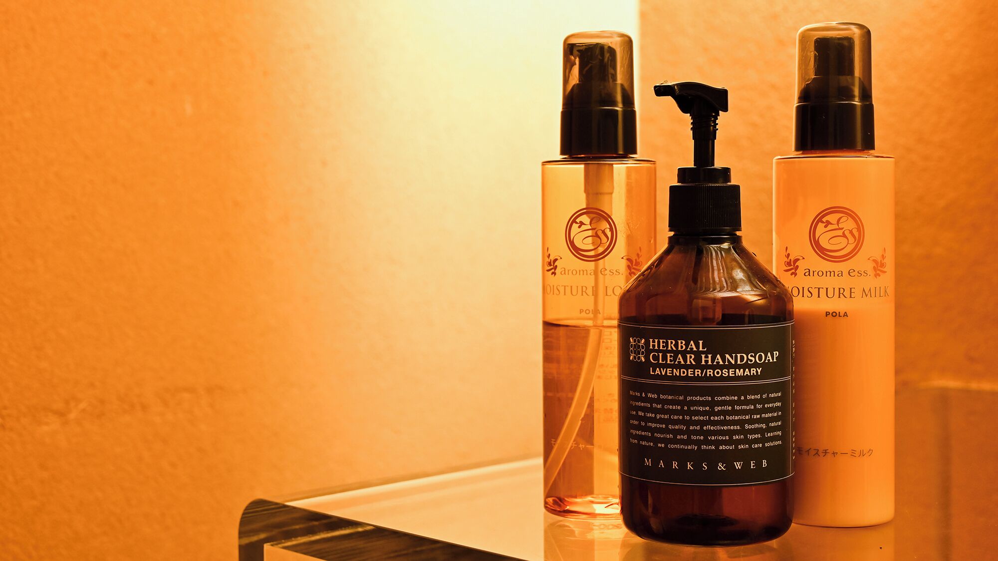 Three bottles of hand soap on a reflective surface.
