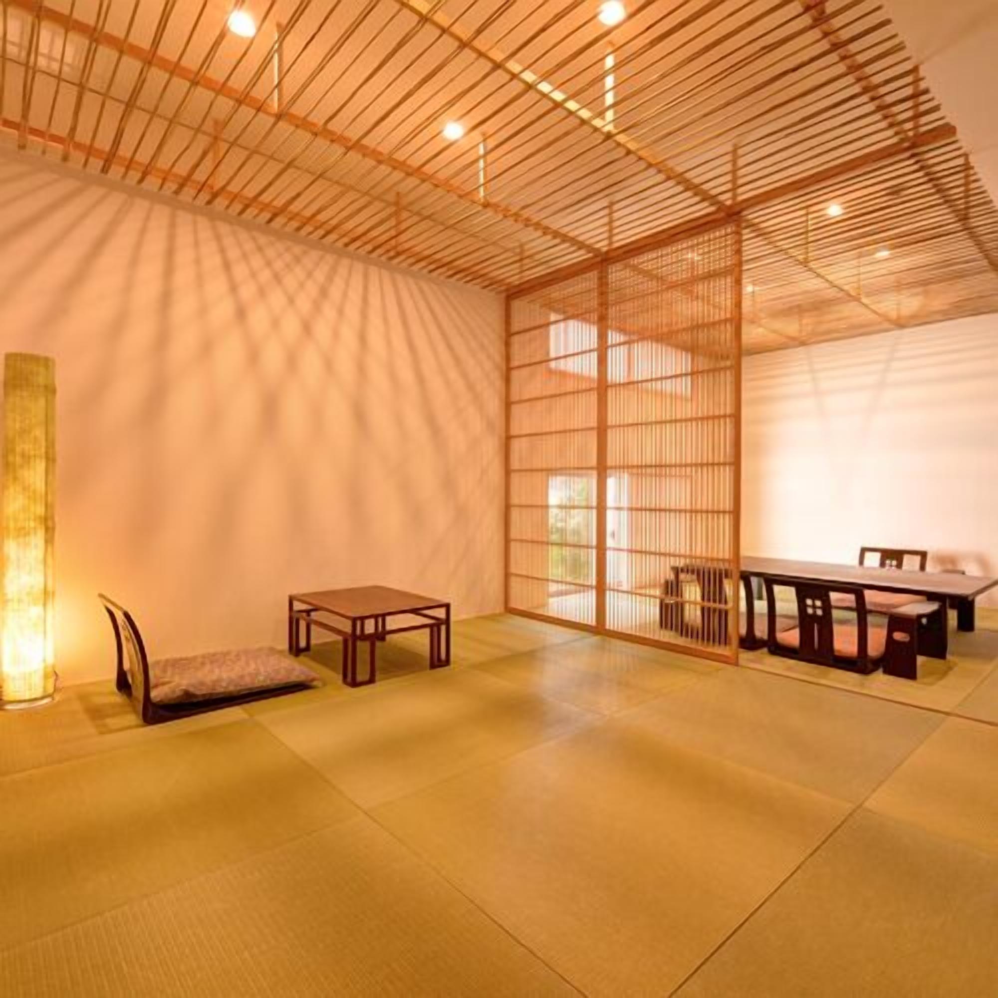 A traditional Japanese room with tatami flooring, a low table with chairs, and a sliding door.
