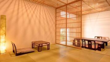 A traditional Japanese room with tatami flooring, a low table with chairs, and a sliding door.