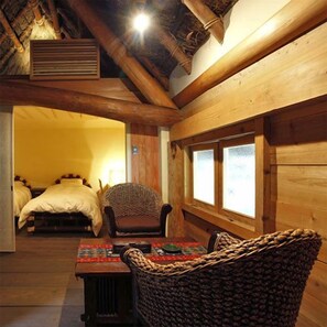 A cozy room with a wooden ceiling, a table with a woven chair, and a bed with a headboard. - Ryokan Yunokawa Onsen Shoen (Izumo)