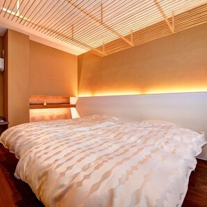 A modern bedroom with a large bed, a headboard with built-in lighting, and a sloped ceiling design. - Ryokan Yunokawa Onsen Shoen (Izumo)