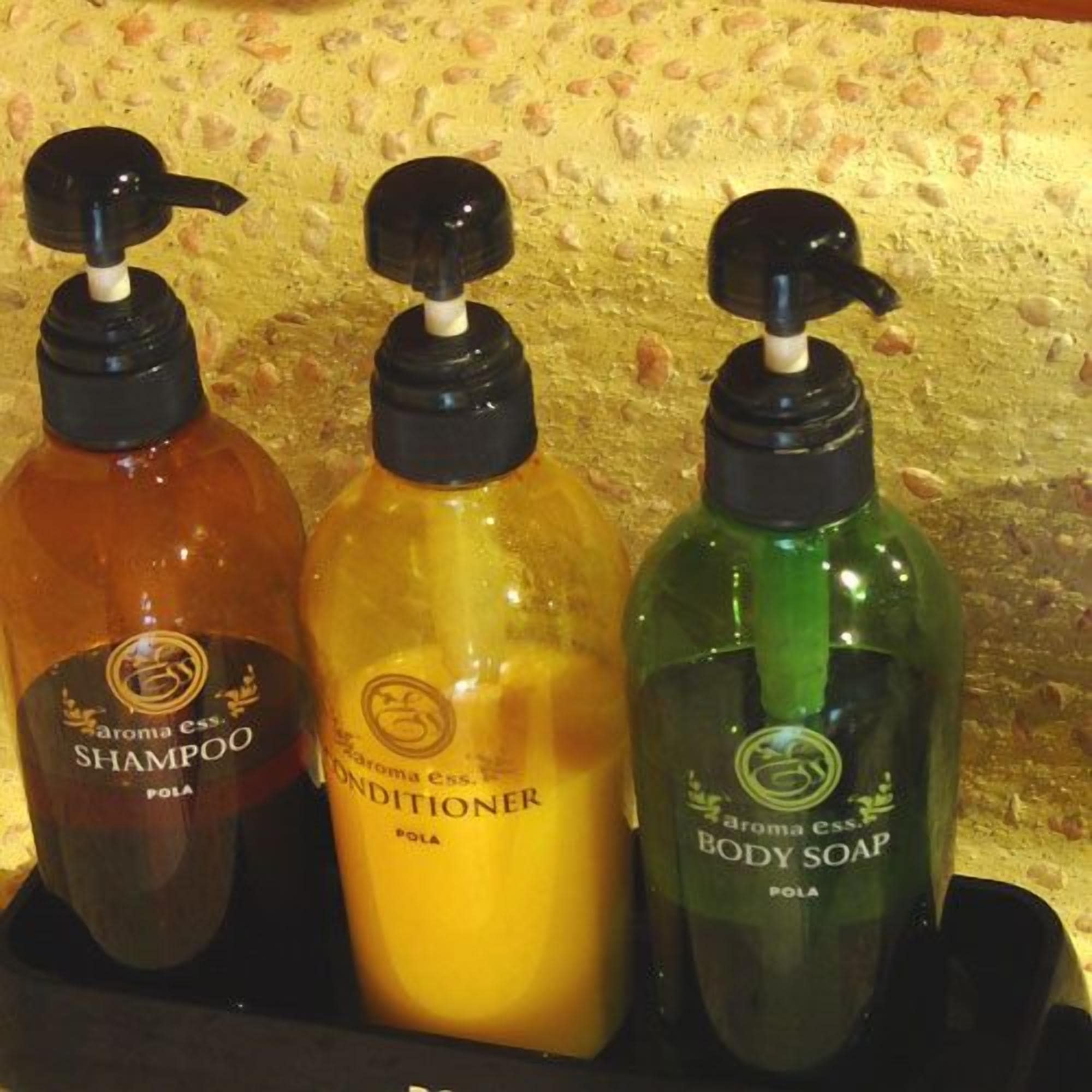 Kolme pumppupulloa, jotka sisältävät vartalonhoitotuotteita ja joissa on etiketit, joista ilmenee, että ne ovat shampoo-, hoitoaine- ja vartalosaippua.