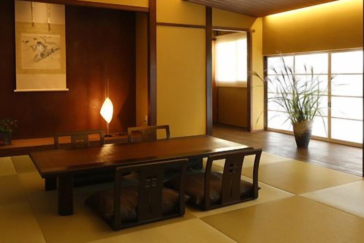 Una habitació tradicional japonesa amb terra de tatami, una taula baixa amb coixins i una porta corredissa.