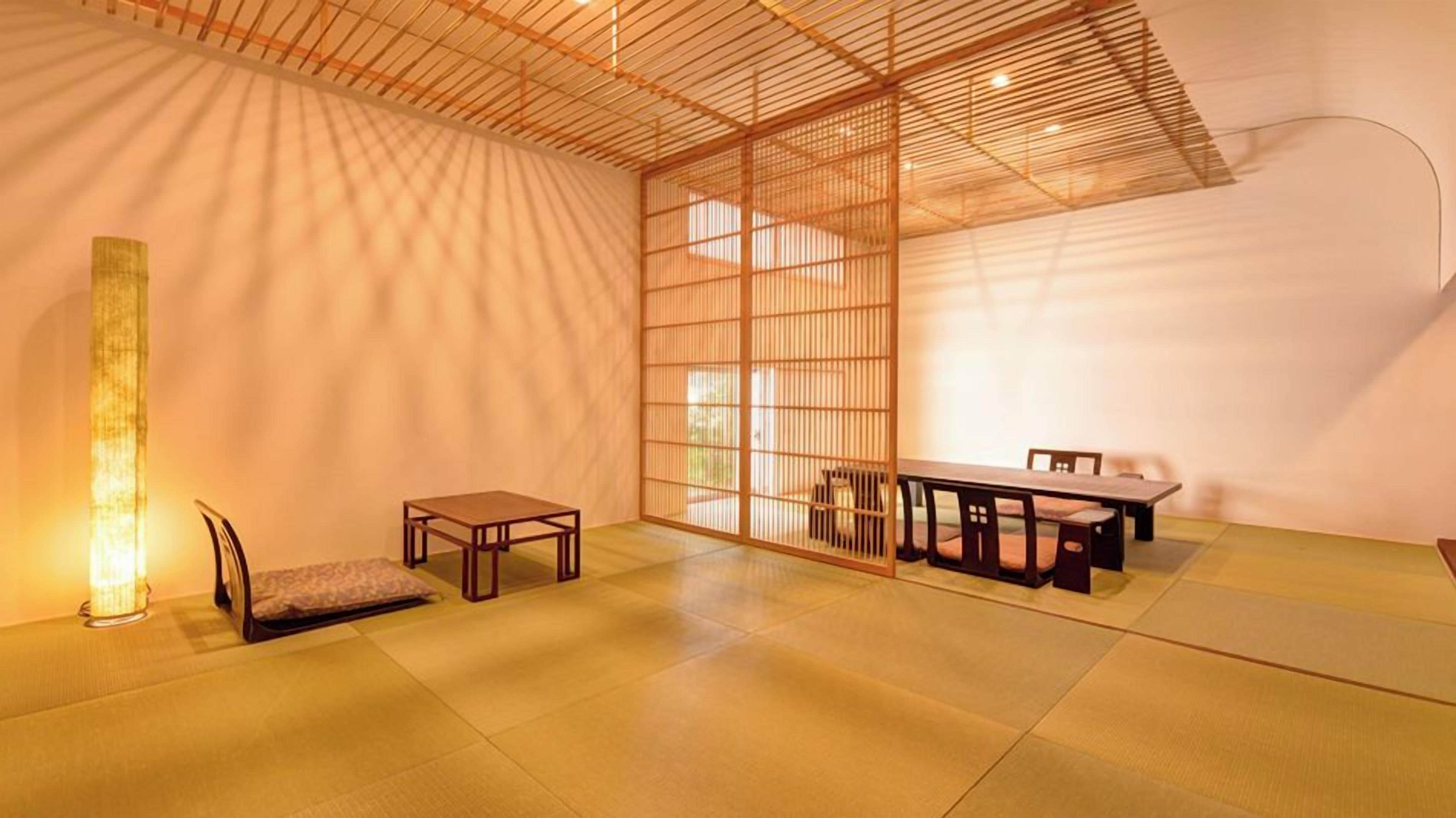 Une pièce de style japonais traditionnel, avec un sol recouvert de tatamis, une table basse, un banc et une porte coulissante.