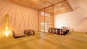 Une pièce de style japonais traditionnel, avec un sol recouvert de tatamis, une table basse, un banc et une porte coulissante.