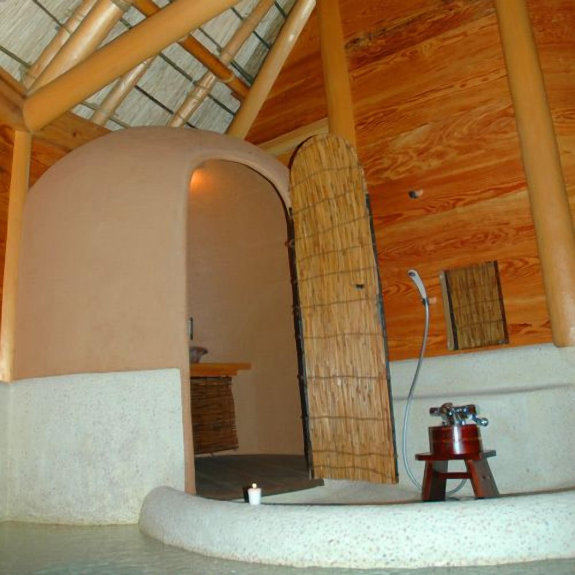 A spa room with a wooden ceiling, a stone bench, and a small wooden cabinet.