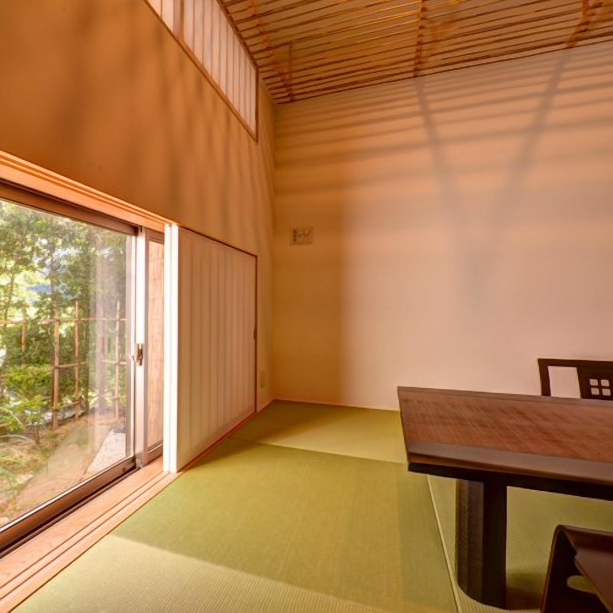 A room with tatami flooring, a sliding door, and a table with chairs.
