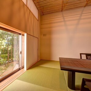 Una habitación con suelo de tatami, puertas correderas y una mesa con sillas.