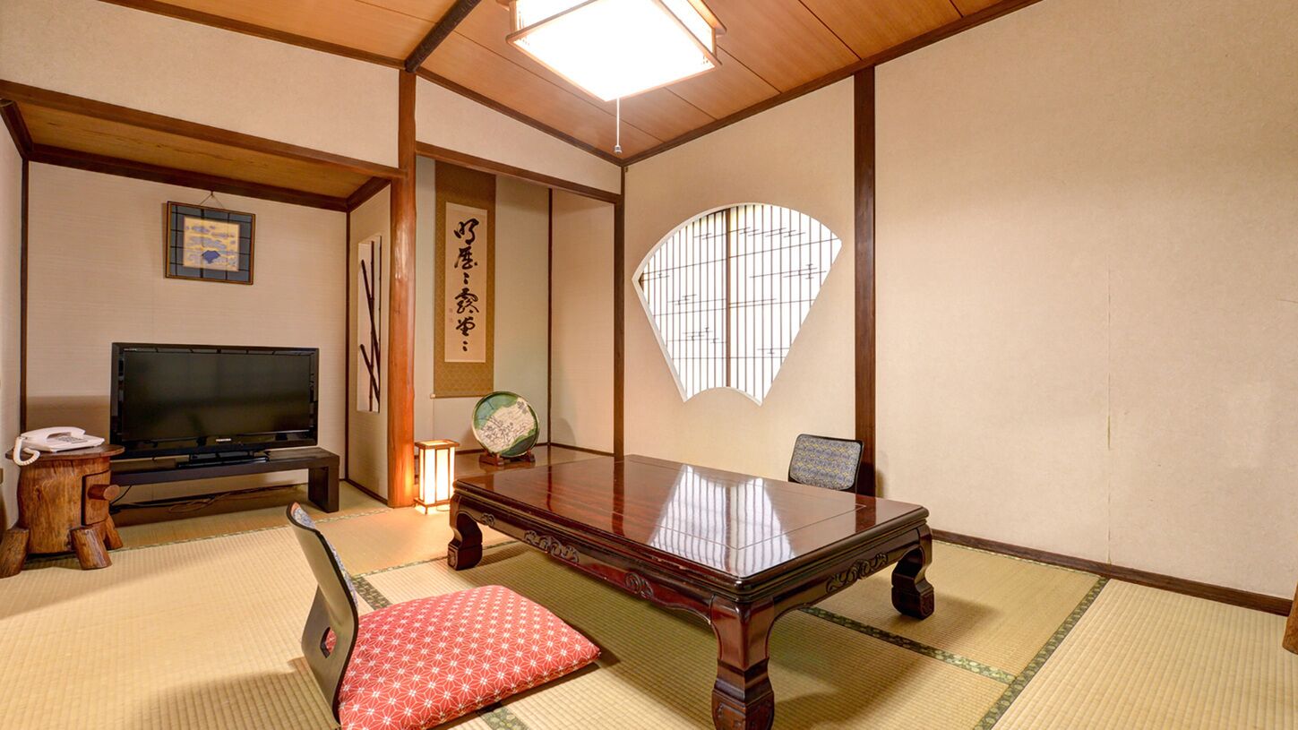 Una habitación japonesa tradicional con suelo de tatami, una mesa baja, un televisor y una pantalla decorativa.