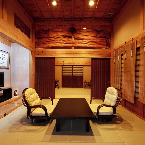 A traditional Japanese-style room with tatami flooring, a low wooden table, and two tatami mat chairs. - Ryokan Yunokawa Onsen Shoen (Izumo)