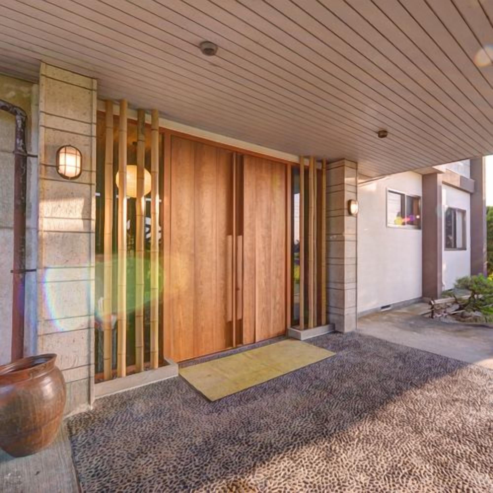 A modern building entrance with a wooden door, stone walls, and a gravel pathway.