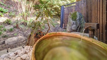 A hot spring with a wooden bench and a bamboo fence in the background.