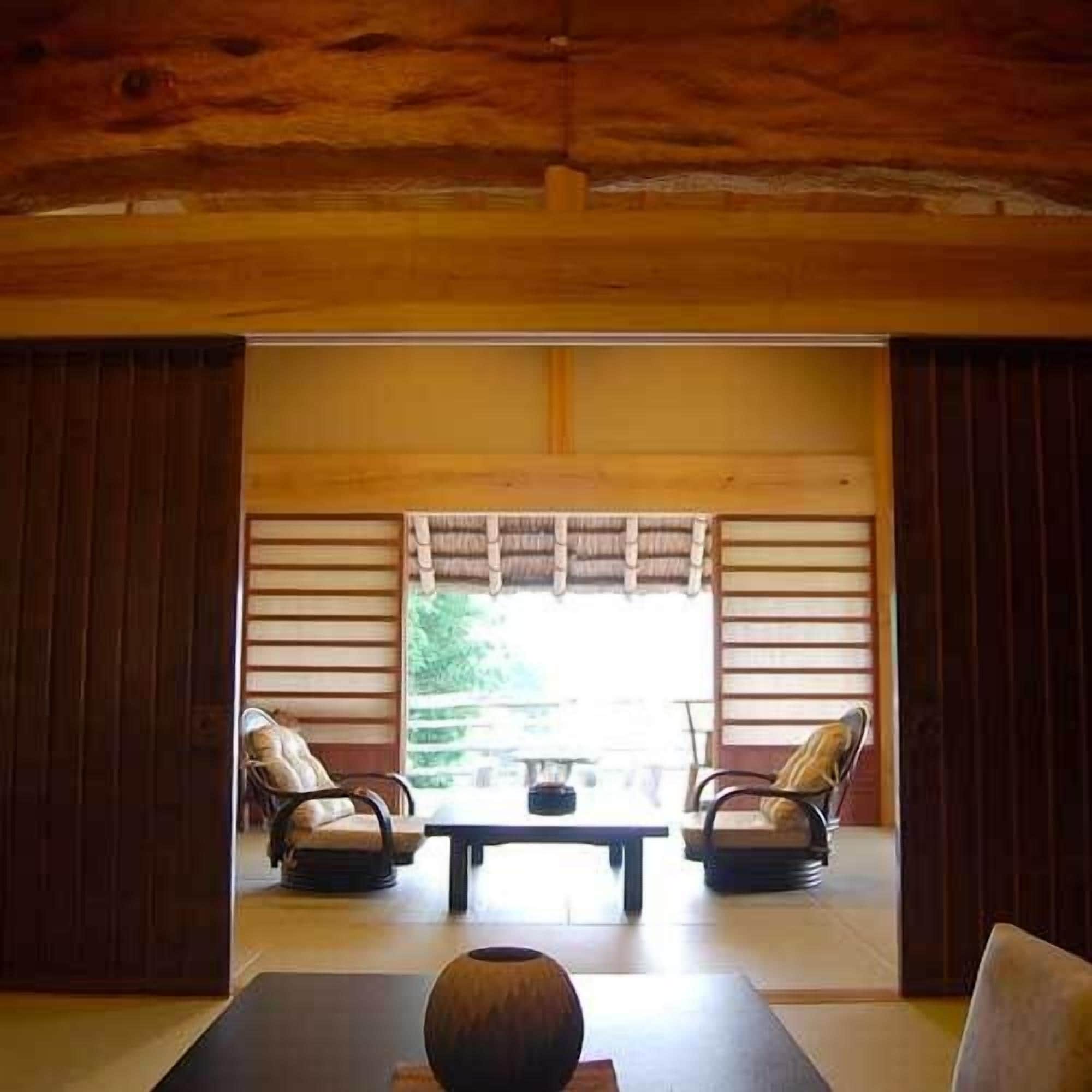 Une pièce de style japonais traditionnel, avec un sol recouvert de tatamis, une table basse et deux fauteuils rembourrés.