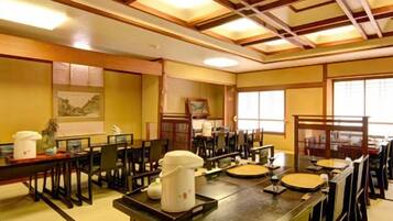 A traditional Japanese-style dining room with tatami mats, wooden tables, and chairs.