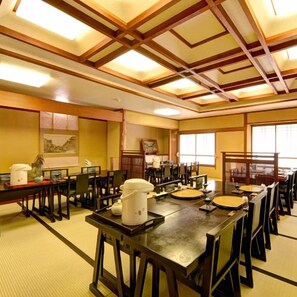 Un comedor tradicional japonés con esteras de tatami, mesas y sillas de madera.