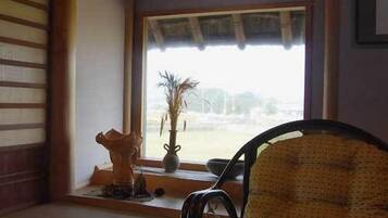 Une pièce avec une fenêtre, une chaise, une table et un vase décoratif.
