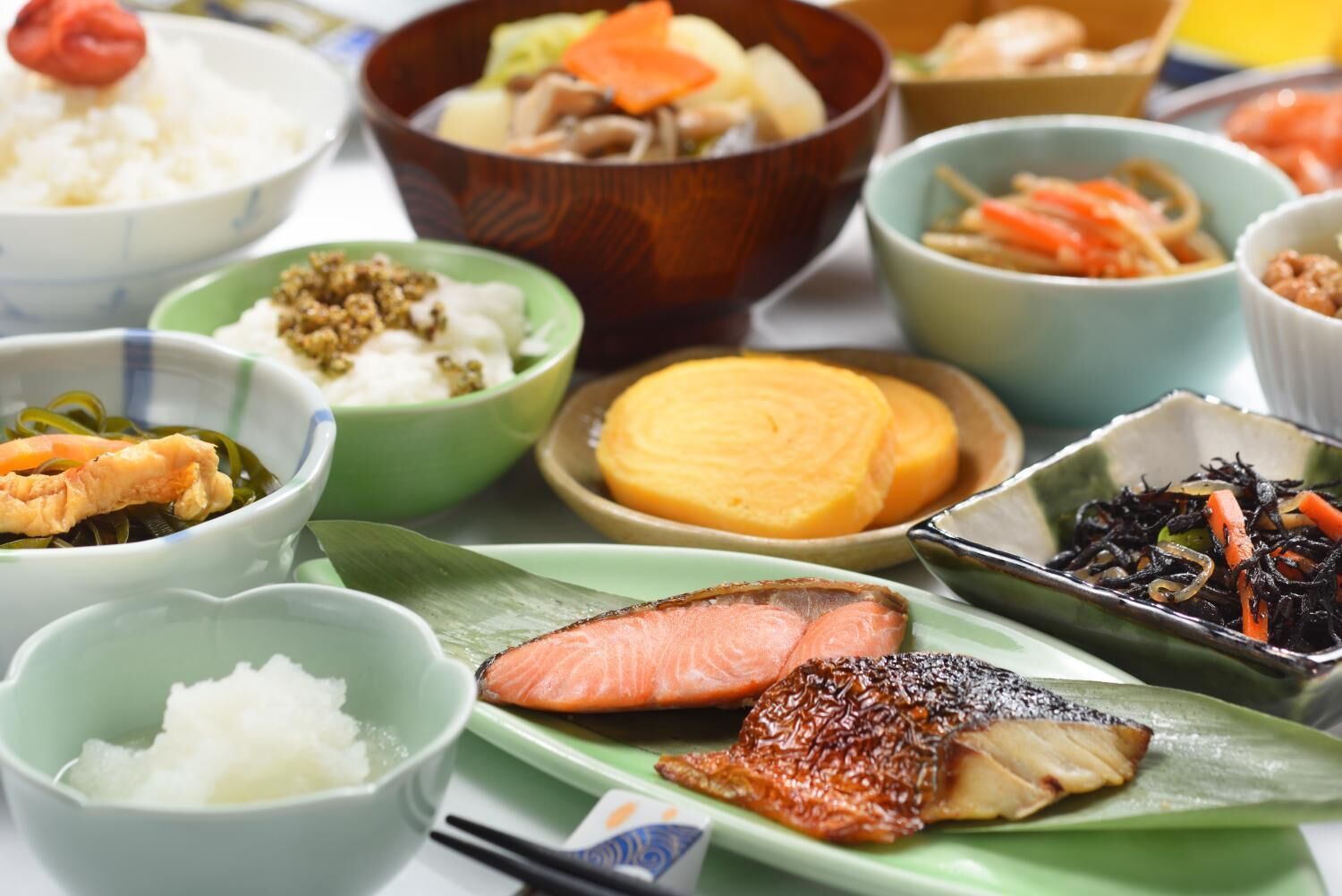 A variety of Japanese dishes including sushi, sashimi, and other traditional foods arranged on a table.