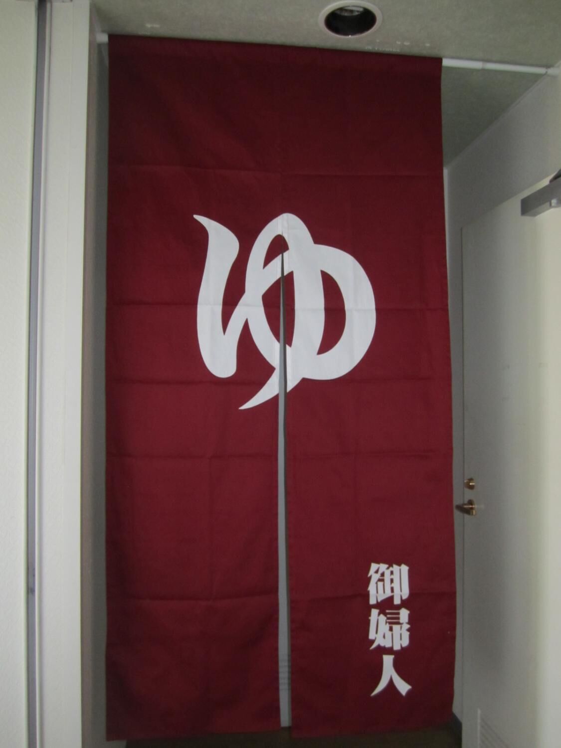 A red banner with white text and a symbol, hanging in a doorway.