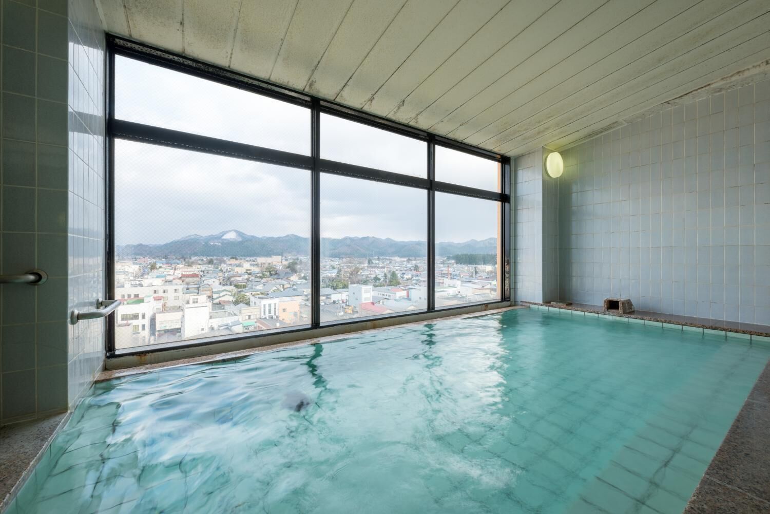 An indoor swimming pool with large windows offering a cityscape view.