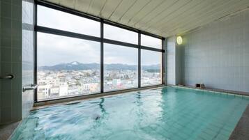 An indoor swimming pool with large windows offering a cityscape view.
