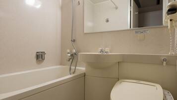 Un baño moderno con bañera, inodoro y un espejo sobre el lavamanos.