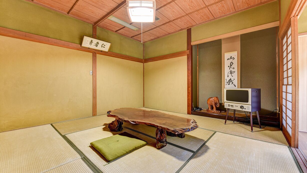 A traditional Japanese room with tatami flooring, a low wooden table, and a television.