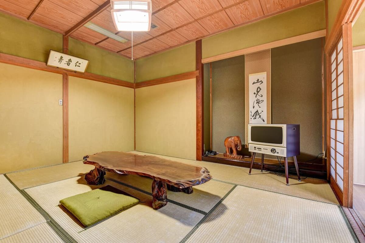 Une pièce de style japonais traditionnel, avec un sol recouvert de tatamis, une petite table en bois et un téléviseur.