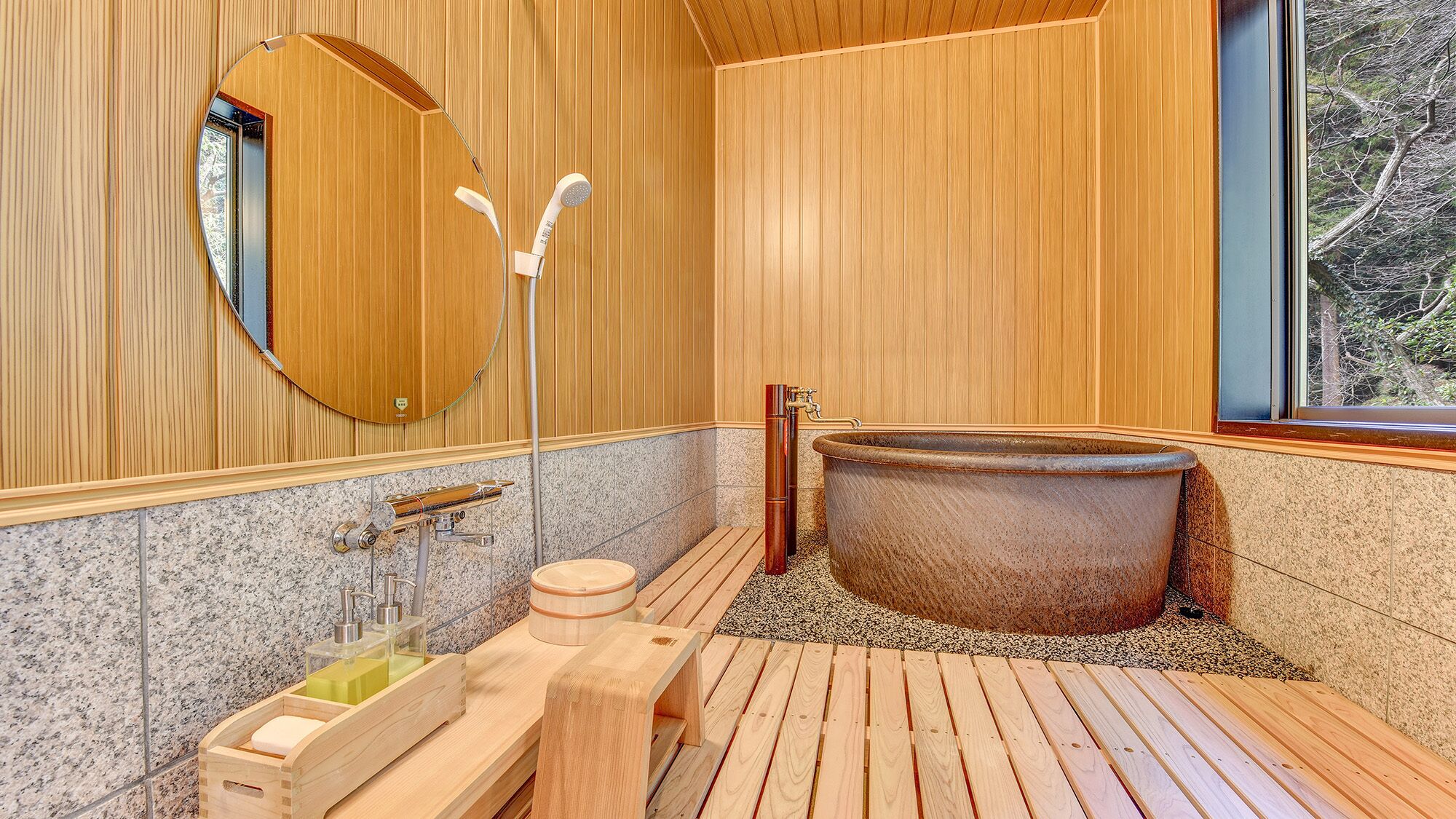 A wooden interior with a large bathtub, a wooden bench, a sink with soap dispensers, and a mirror on the wall.