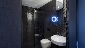 Een moderne badkamer met een douchecabine van glas, een wit toilet en een witte wastafel.