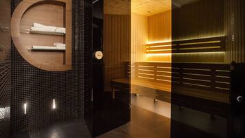 Bathroom features a circular vanity, mirror, and towel rack, along with a bench and black tiled wall.